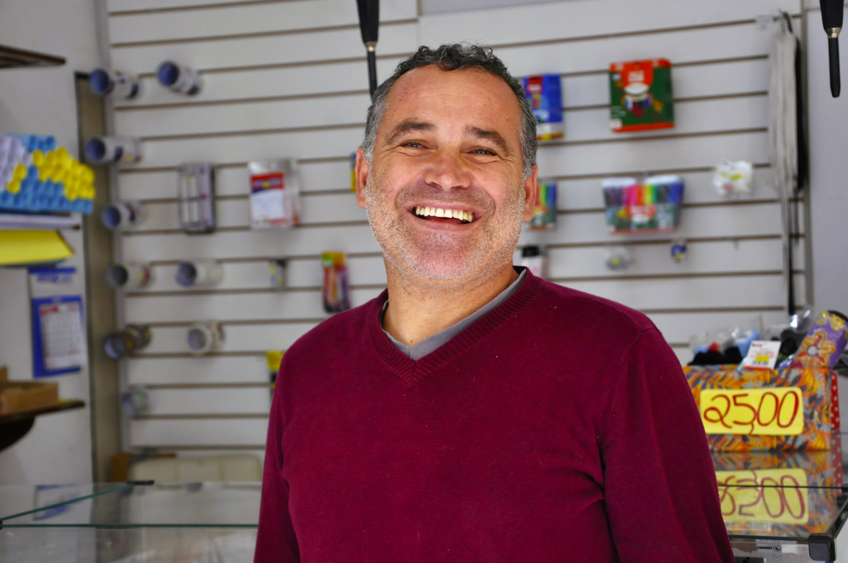 Na imagem, vemos o empreendedor Sandro Silva em sua LanHouse. Sandro é um jovem senhor branco. Na foto, ele usa uma blusa vermelha.